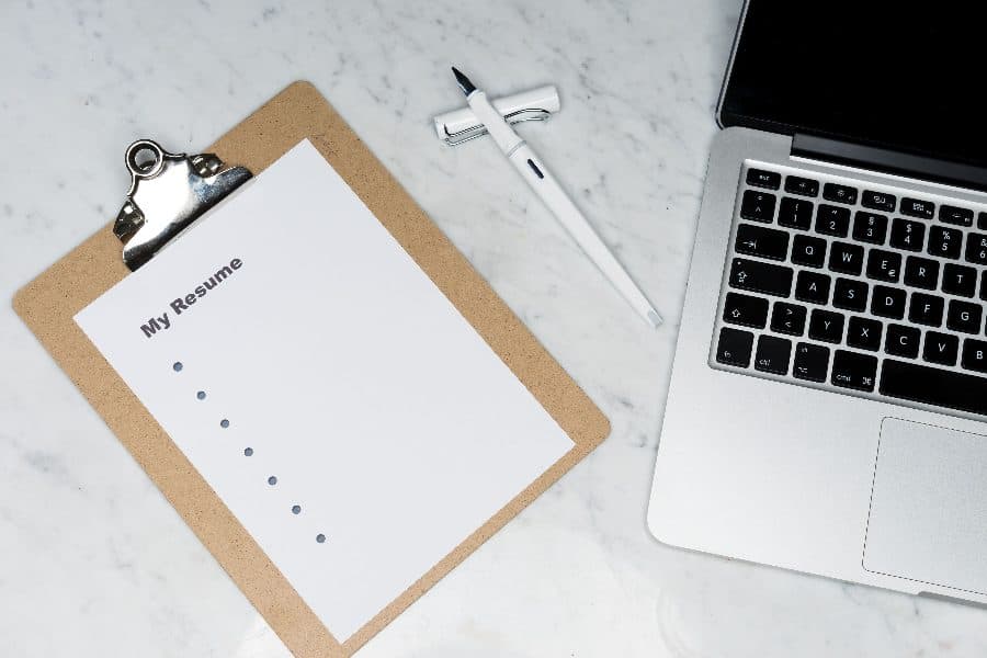 Un CV vierge sur une planchette à côté d'un ordinateur portable